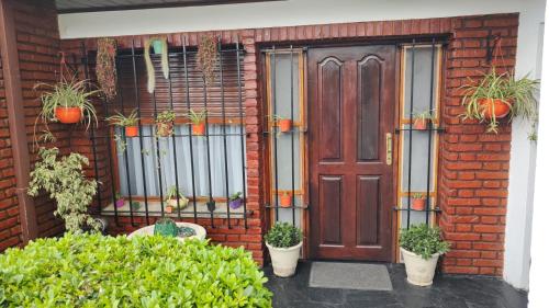 a red brick house with a wooden door and potted plants at Chalet residencial Maroli in Mar del Plata