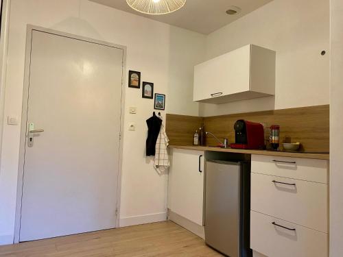 - une cuisine avec des placards blancs, un évier et une porte dans l'établissement Appartement proche Centre-ville- Fibre, à Saint Lo