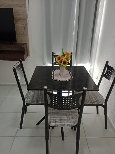 a black table with two chairs and a vase with flowers at Plaza Fraga Maia in Feira de Santana