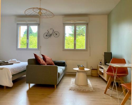 ein Wohnzimmer mit einem Sofa, einem Bett und Fenstern in der Unterkunft Appartement proche Centre-ville- Fibre in Saint Lo