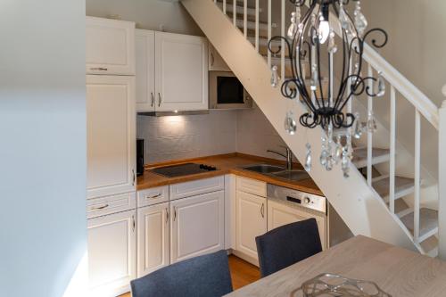a kitchen with white cabinets and a chandelier at Apartmenthaus Haus Sonne I direkt am Strand in Dierhagen