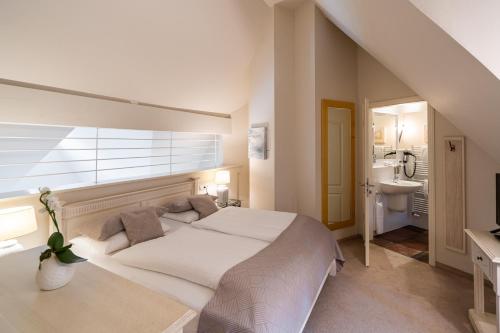 a white bedroom with a large bed and a sink at Apartmenthaus Haus Sonne I direkt am Strand in Dierhagen