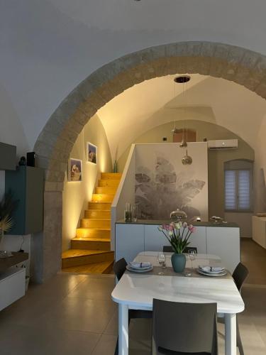 a dining room with a white table and a staircase at Alma B&B in Trani