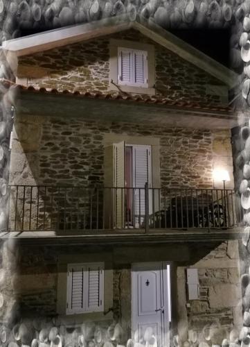 a stone building with a balcony and two windows at Casa do Rossio in Fornos