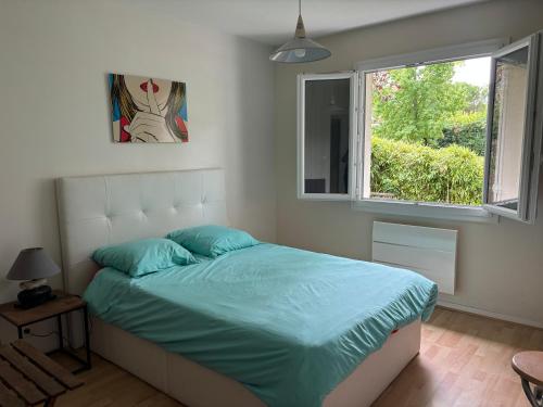 une chambre avec un lit avec des draps bleus et une fenêtre dans l'établissement Beau T2 meublé récent, à Bouliac