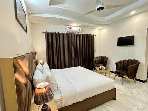 a hotel room with a bed and two chairs at Western Lodge Guest House Islamabad in Islamabad