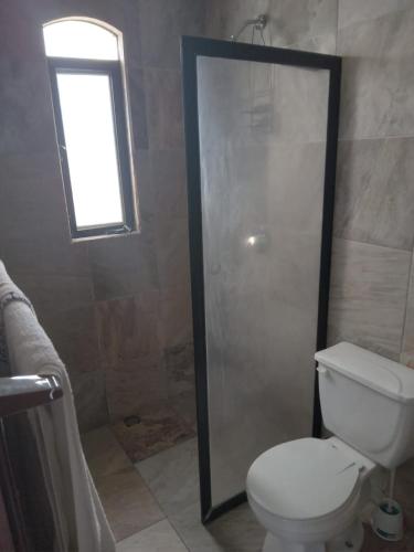 a bathroom with a shower and a toilet and a window at Casona in San José del Cabo