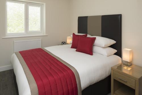 a bedroom with a large bed with red pillows at House of Fisher - Beneficial House in Bracknell