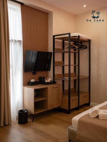 a room with a tv and a bookcase with a television at Da Zara Hotel in Lalzit Bay