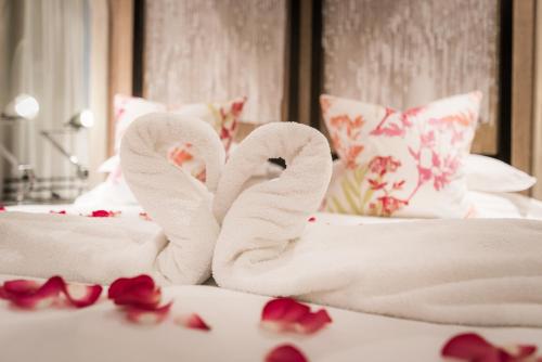 two towel swans sitting on a bed with roses at Hout Bay Manor in Hout Bay