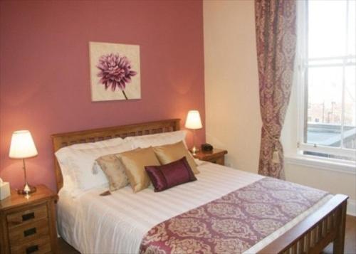 Un dormitorio con una cama y dos lámparas y una ventana. en The Imperial Apartment, en North Berwick