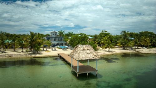 a dock in the water in front of a house at Conmigo Villas - 6 Bedroom Beachfront with Pool in Maya Beach