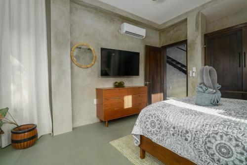 a bedroom with a bed and a tv and a dresser at Conmigo Villas - 6 Bedroom Beachfront with Pool in Maya Beach
