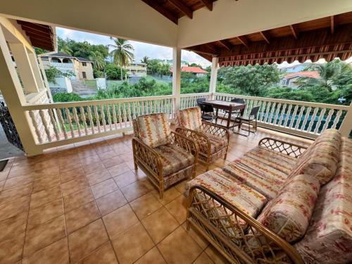 a porch with a couch and chairs and a table at Chalet Belizomi - La Marguerite Room in Rodney Bay Village
