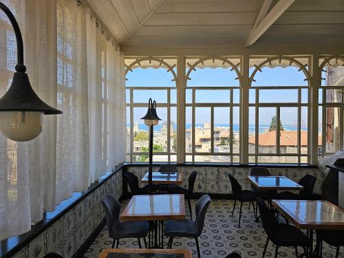 a restaurant with tables and chairs and windows at כוהנ'ס Cohen's Boutique Hotel in Haifa