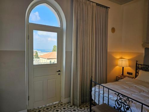 a bedroom with a bed and a large window at כוהנ'ס Cohen's Boutique Hotel in Haifa