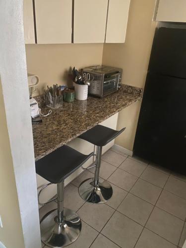 a kitchen with a counter with two stools and a microwave at Botanical Tranquility in Orlando