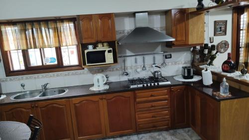 a kitchen with wooden cabinets and a sink and a microwave at Chalet residencial Maroli in Mar del Plata