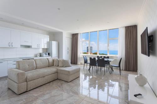 a living room with a couch and a table with chairs at Odesa Pearl Apartments in Odesa