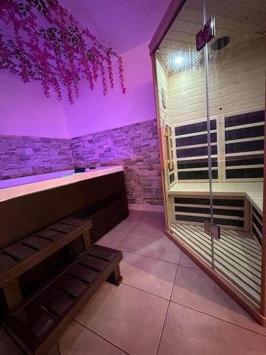 La salle de bains est pourvue d'une douche à l'italienne avec un éclairage violet. dans l'établissement Suite 110 Jacuzzi et Sauna privatisé avec suite, à Esbly