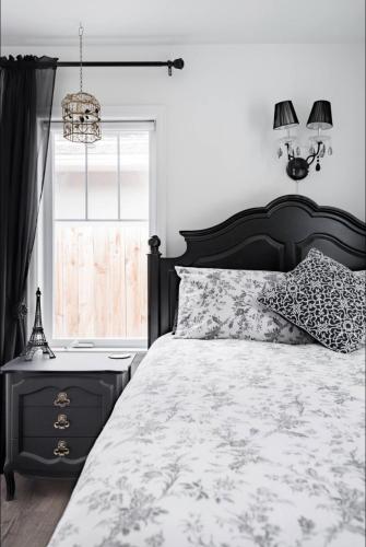 a bedroom with a black and white bed and a window at Ivywild Boutique Cottage in Broadmoor