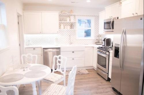 a white kitchen with a table and a refrigerator at Ivywild Boutique Cottage in Broadmoor