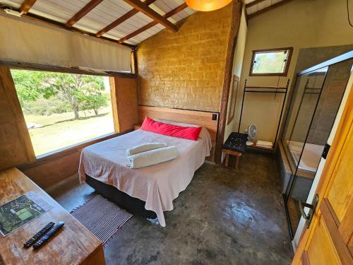 a bedroom with a bed in a room with a window at Chalés Vila Carrancas - Ao lado do centro com piscina, cozinha completa e muita tranquilidade in Carrancas