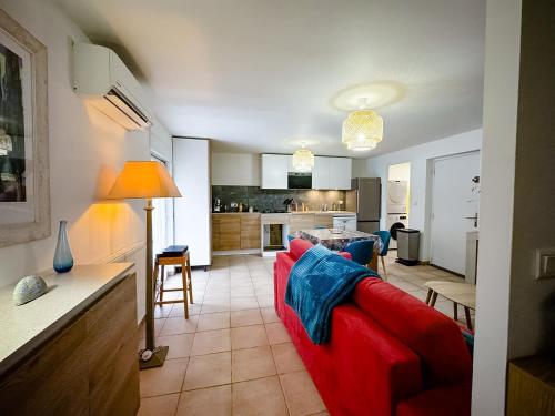 un salon avec un canapé rouge et une cuisine dans l'établissement DREAM HOLIDAY 26 - Charmant T2 4 Pers 38m2 - Clim, Wifi, Parking - Sur RN7 au calme - au cœur de Livron sur Drôme à 5Km l'Autouroute Proximité A7, à Livron-sur-Drôme