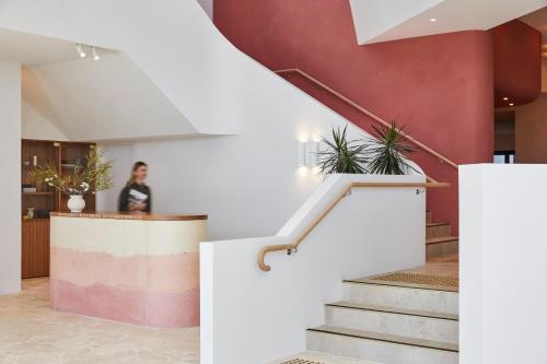 a woman standing in a lobby with stairs and plants at The Clairfield Hotel in Mudgee