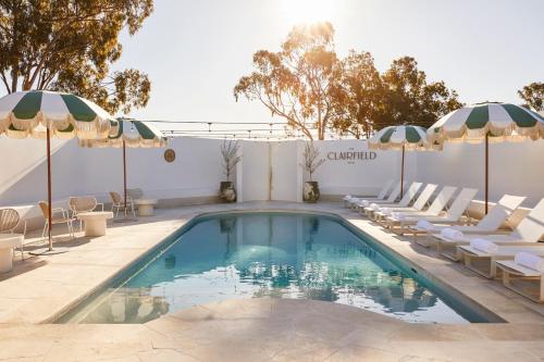 a swimming pool with lounge chairs and umbrellas at The Clairfield Hotel in Mudgee