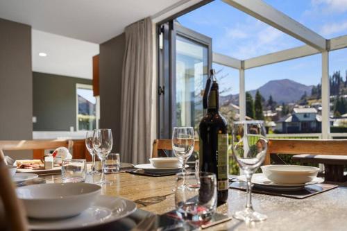 a dining table with a bottle of wine and glasses at *** LAKE VILLA 457 *** in Hanmer Springs