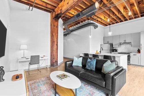 a living room with a black couch and a table at Brick & Bed Riverfront Lofts, G 201 in Saint Louis