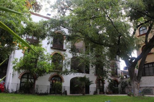 a white building with windows and a tree at Depa en Privada en el centro con estacionamiento in San Miguel de Allende