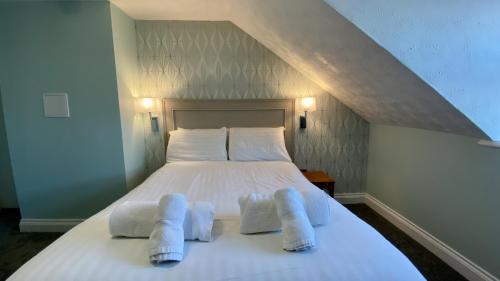 a white bed with two towels on top of it at The Fairhaven Hotel in Weymouth