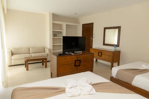 a hotel room with two beds and a flat screen tv at Quinto Sole in Mahahual