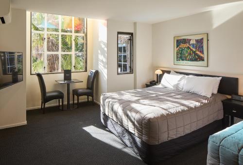 a hotel room with a bed and a table and chairs at Pavilions Hotel in Christchurch