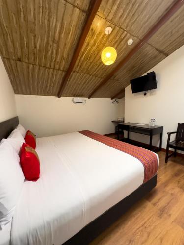 a bedroom with a large white bed with red pillows at Hotel San Pedro Plaza in Cusco