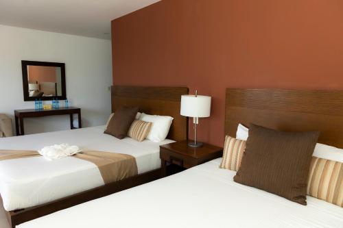 a hotel room with two beds and a mirror at Quinto Sole in Mahahual