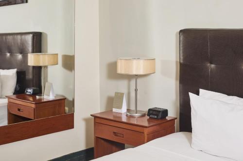 a bedroom with a bed with a lamp and a mirror at El Dorado Classic Hotel in Iquitos