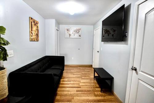 a living room with a black couch and a television at Lovely Loft in Newark Minutes from NYC, EWR & American Dream Mall in Newark