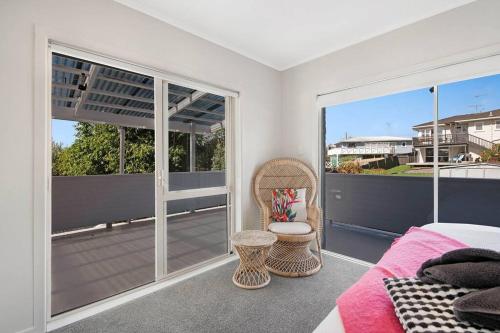 a bedroom with a bed and a balcony at Pohutukawa Estuary Views in Red Beach