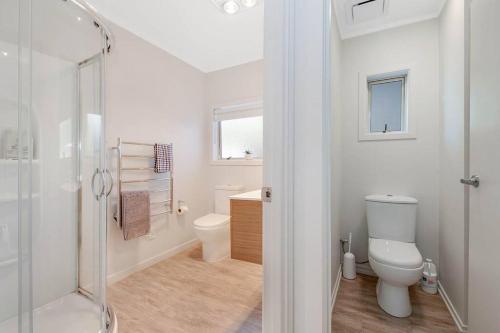 a white bathroom with a shower and a toilet at Pohutukawa Estuary Views in Red Beach