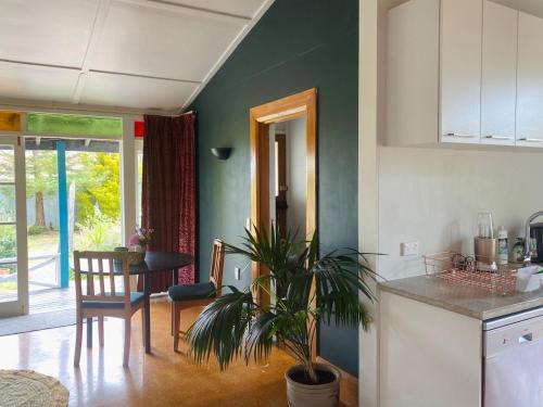 a kitchen and dining room with a table and a plant at Havelock North Cottage on Organic Orchard in Havelock North