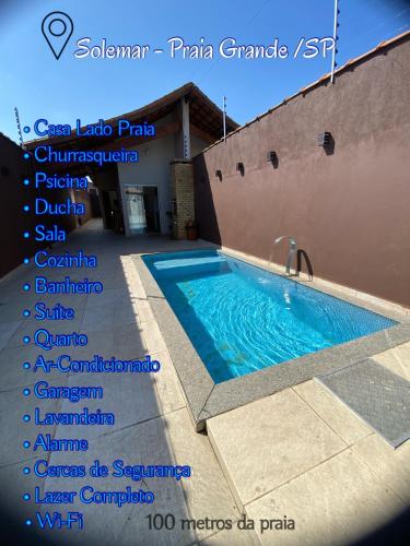 ein Schild für ein Schwimmbad neben einem Gebäude in der Unterkunft Casa de PRAIA Solemar PG 2 quarteirão do MAR in Praia Grande