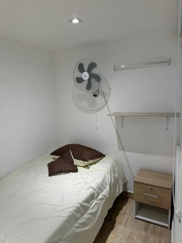 a white bedroom with a bed and a fan at Habitaciones tipo hotel con terraza in Ibagué