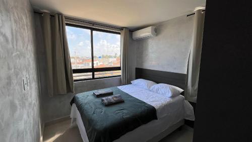 a bedroom with a bed with a large window at Flat Comfort La Belle Formosa - Cabedelo in Cabedelo