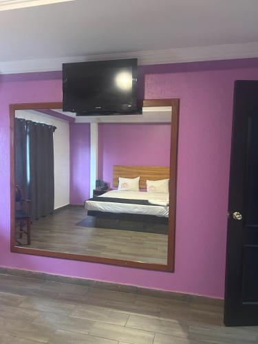 a mirror in a room with a bed with purple walls at Auto Hotel El Cine in El Jobo
