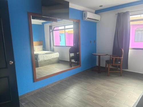 a mirror in a blue room with a bed and a table at Auto Hotel El Cine in El Jobo