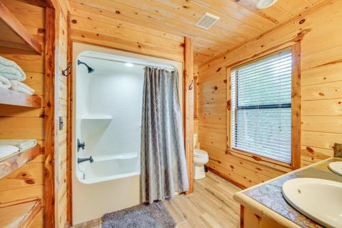 a bathroom with a tub and a toilet and a sink at Cabin with Hot Tub and Wraparound Deck in Broken Bow! in Broken Bow