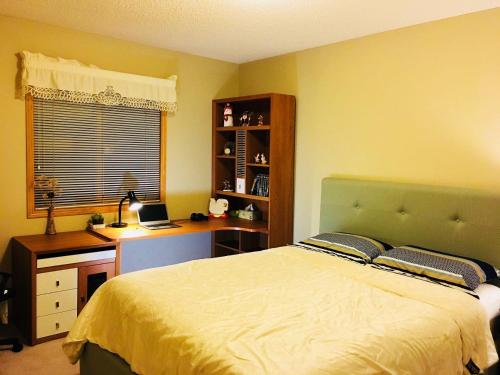 a bedroom with a bed and a desk with a laptop at Bedrooms in Kenaston, Close to Walmart, Costco, IKEA, Outlet in Winnipeg